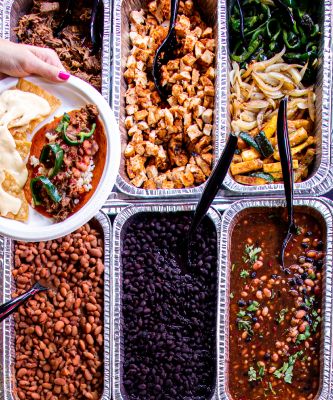 Catering trays with beans and other taco fillings.