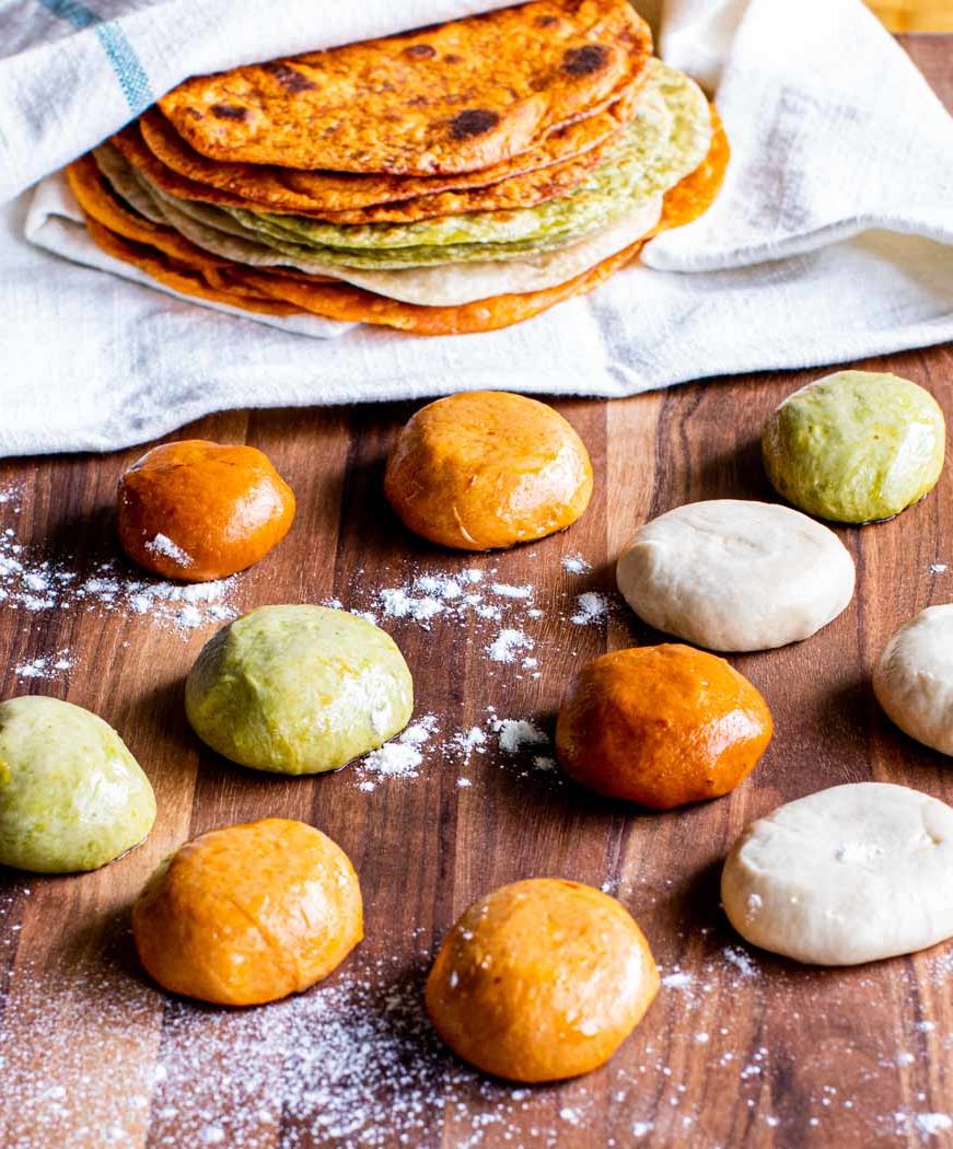 Build Your Own 7 Multicolored stack of tortillas next to several balls of dough.
