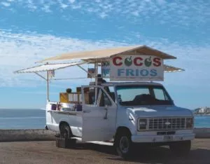 White truck with a shelter over it reading "cocos frios".