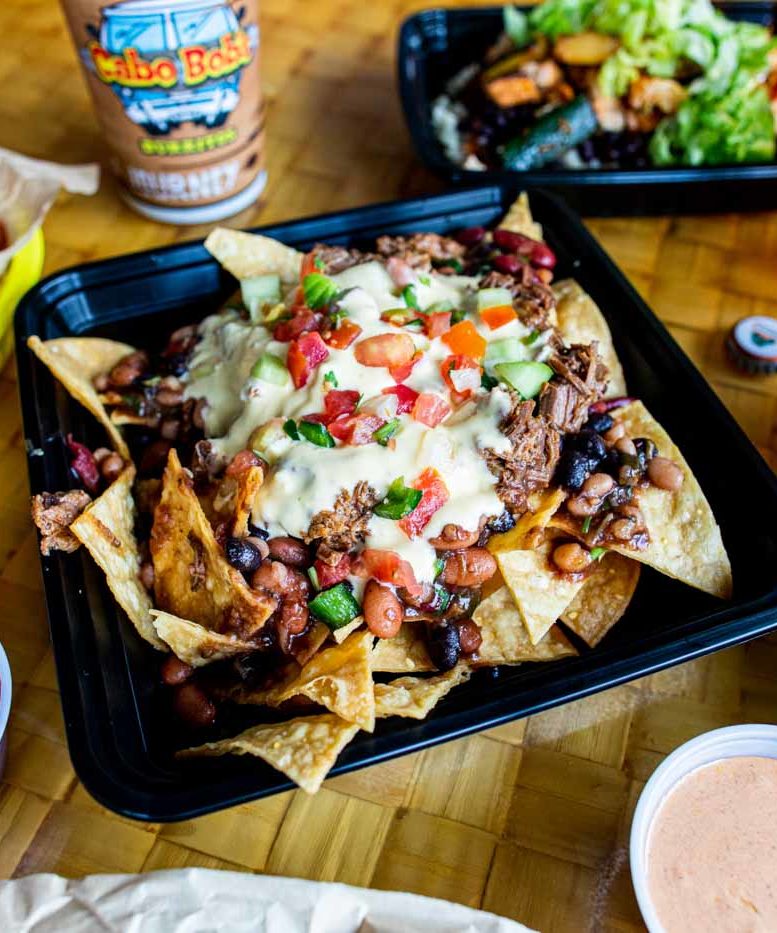 Loaded nachos on a woven rattan surface.